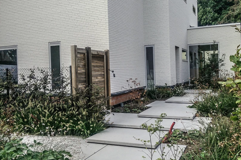 Moderne voortuin met grootformaat betonplaten als trap naar voordeur