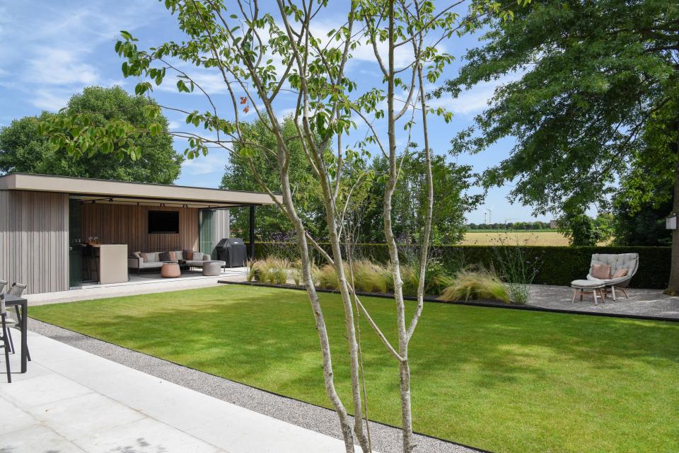 Deze klant koos voor een strak ontwerp. In deze tuin werd een mooie meerstam geplaatst in de terras. Daarnaast werd een oase van rust gecreërd met een grasveld, beplanting en constructies in zwart gelakt staal.