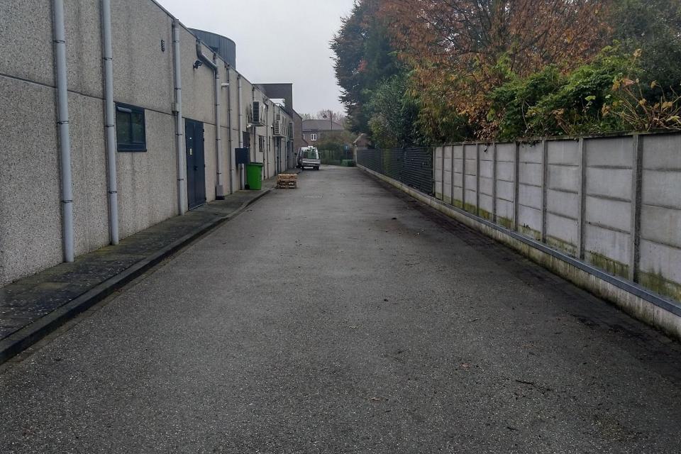 Onderhouden gemeenschappelijke weg achter winkelruimtes.