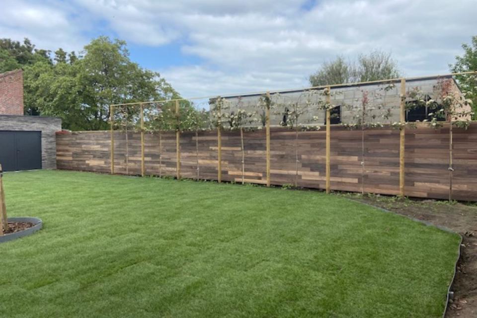 Plaatsen van een wand in padouk en aanleg tuin met grasmatten